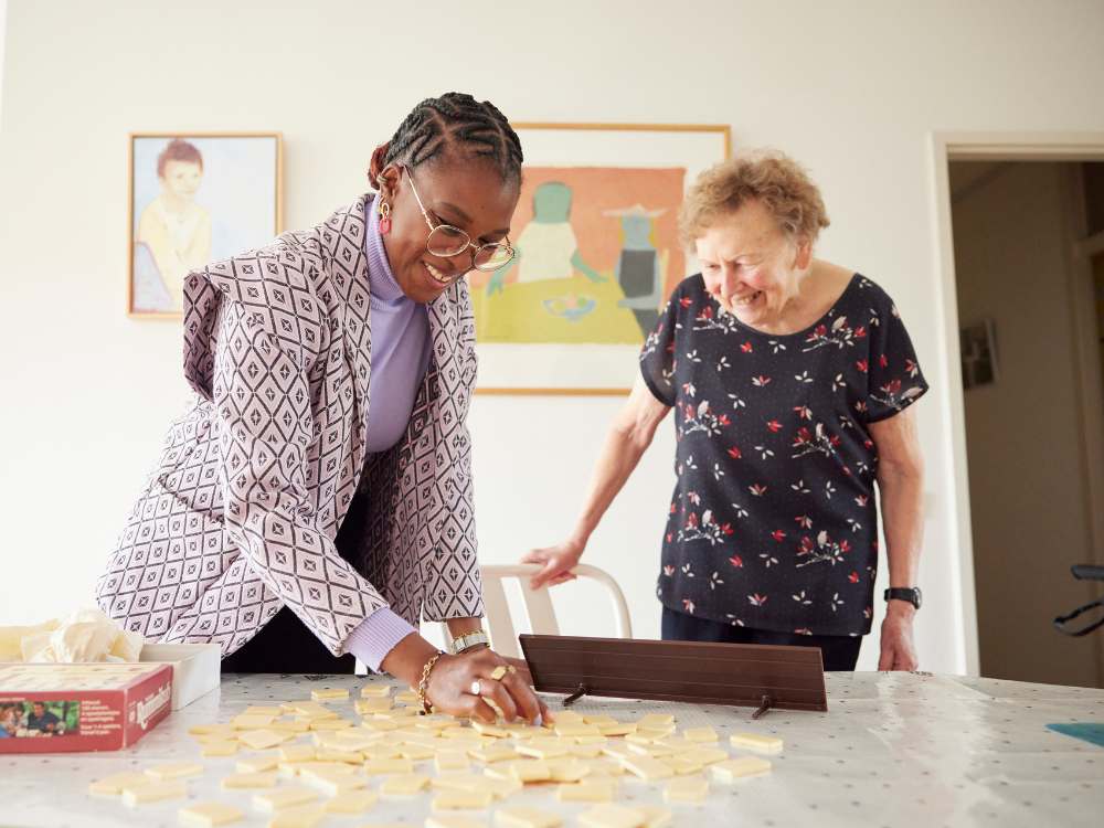 Jongere en senior spelen samen een spel aan tafel